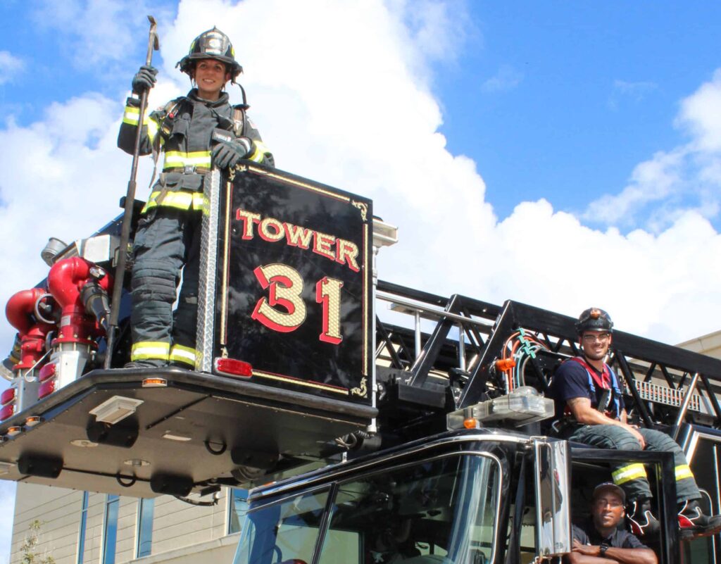 firefighters from tower 31 sit and stand around their ladder truck