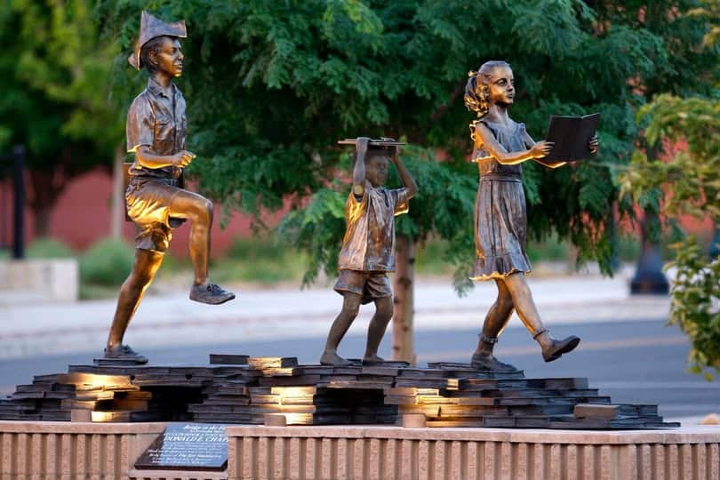 Bridge to the Future statue features three children marching forward. Two are holding books